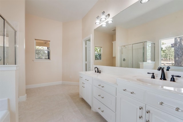 full bathroom with double vanity, a stall shower, baseboards, and a sink