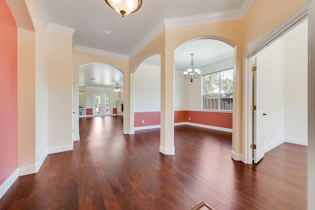 interior space with dark wood-style floors, ornamental molding, arched walkways, and baseboards