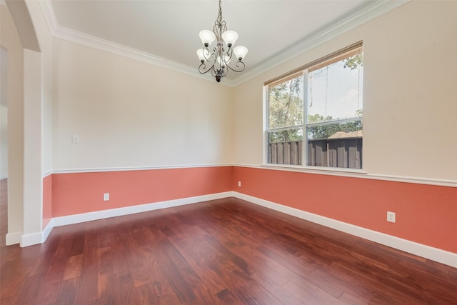 spare room with a chandelier, crown molding, baseboards, and wood finished floors