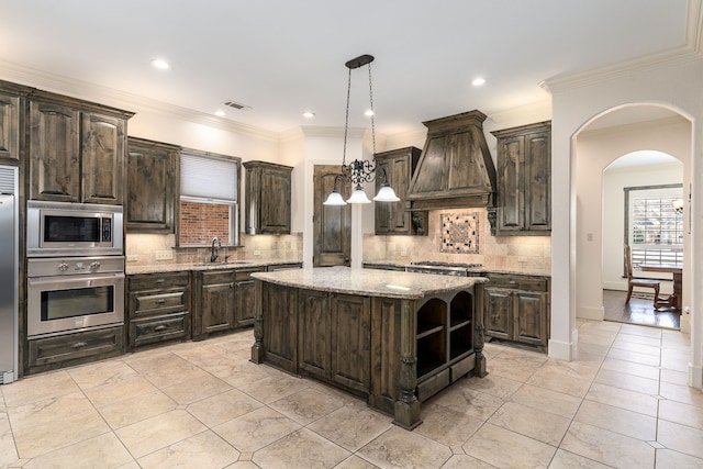 kitchen with dark brown cabinetry, open shelves, visible vents, appliances with stainless steel finishes, and premium range hood