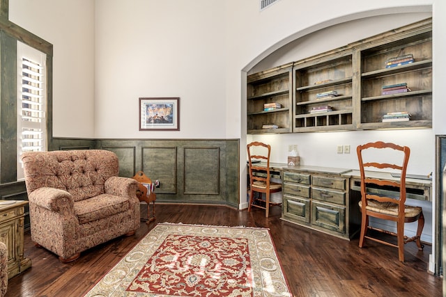office with built in desk, wainscoting, and dark wood finished floors