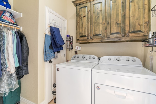 laundry room with cabinet space, baseboards, and washer and dryer