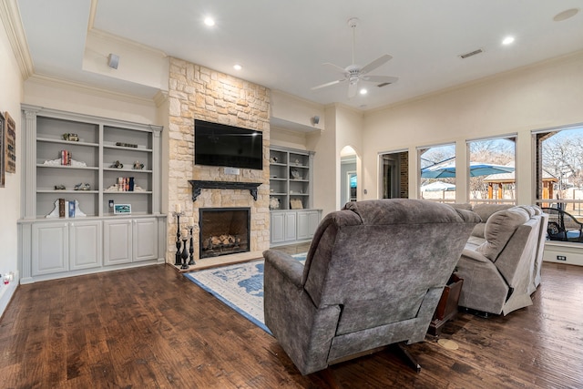 living area with visible vents, a stone fireplace, ornamental molding, and ceiling fan