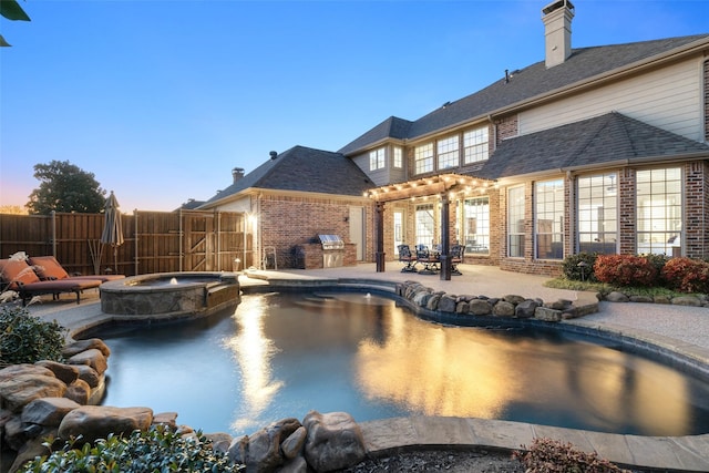 pool at dusk with a patio area, fence, and a pool with connected hot tub