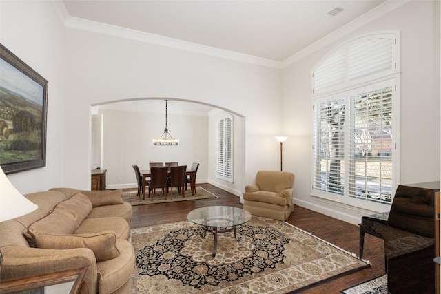 living area with baseboards, arched walkways, wood finished floors, and crown molding