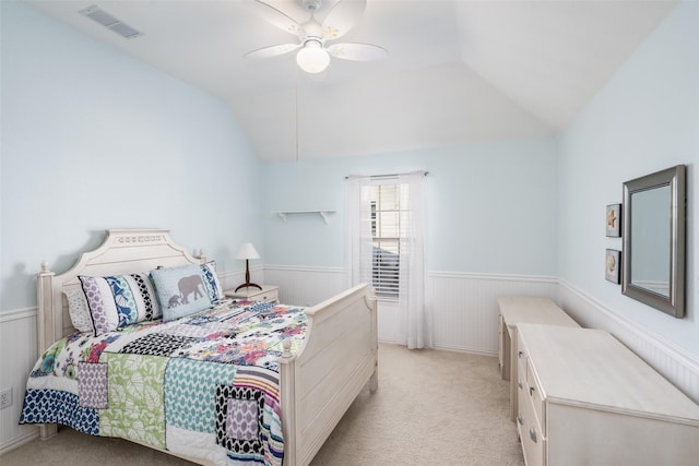 bedroom with lofted ceiling, light colored carpet, and wainscoting