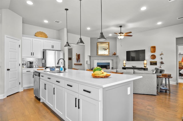 kitchen with appliances with stainless steel finishes, a fireplace, a sink, and light wood finished floors