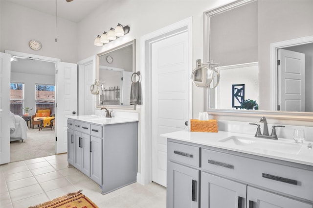 ensuite bathroom with tile patterned flooring, two vanities, a sink, and ensuite bathroom