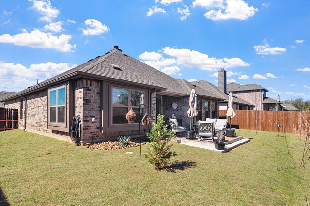 rear view of house featuring a lawn, a patio, a fenced backyard, roof with shingles, and brick siding