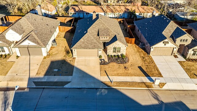 view of front facade featuring concrete driveway, roof with shingles, an attached garage, fence, and brick siding