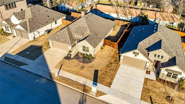 french country style house featuring a garage, brick siding, fence, driveway, and roof with shingles