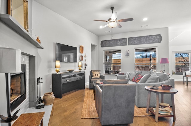 living room with visible vents, ceiling fan, light wood-style floors, a fireplace, and recessed lighting