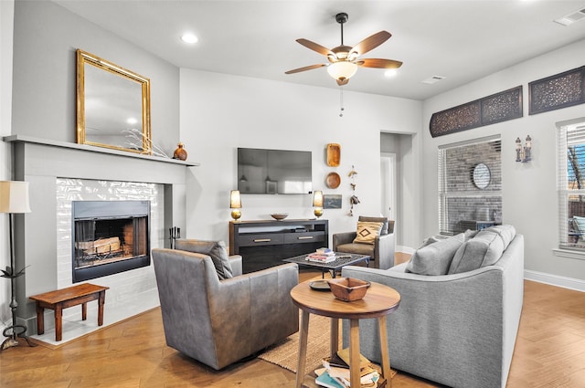 living area with visible vents, a fireplace, baseboards, and wood finished floors