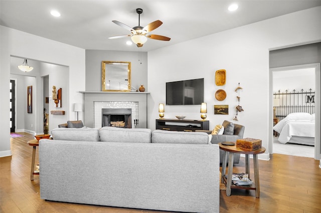 living room featuring a fireplace, recessed lighting, ceiling fan, wood finished floors, and baseboards