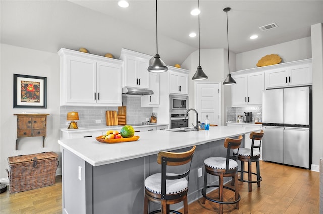 kitchen with visible vents, appliances with stainless steel finishes, under cabinet range hood, white cabinetry, and a sink