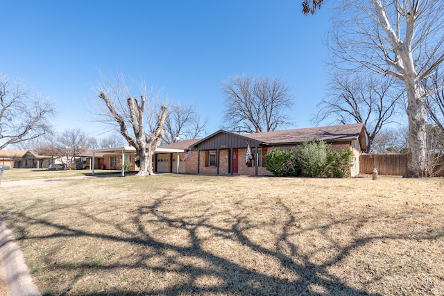 view of front facade with a garage, brick siding, fence, board and batten siding, and a front yard