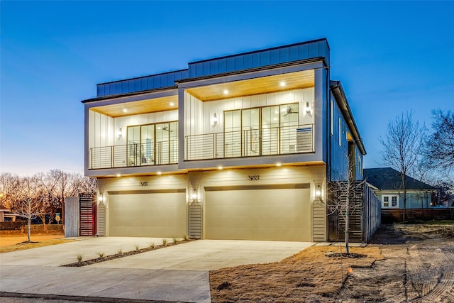 view of front facade featuring board and batten siding, driveway, a balcony, and an attached garage