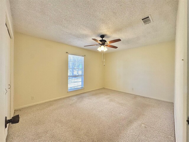 carpeted spare room with baseboards, a textured ceiling, visible vents, and a ceiling fan