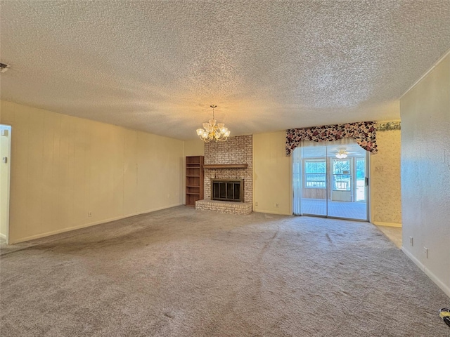 unfurnished living room featuring baseboards, an inviting chandelier, a textured ceiling, carpet flooring, and a brick fireplace