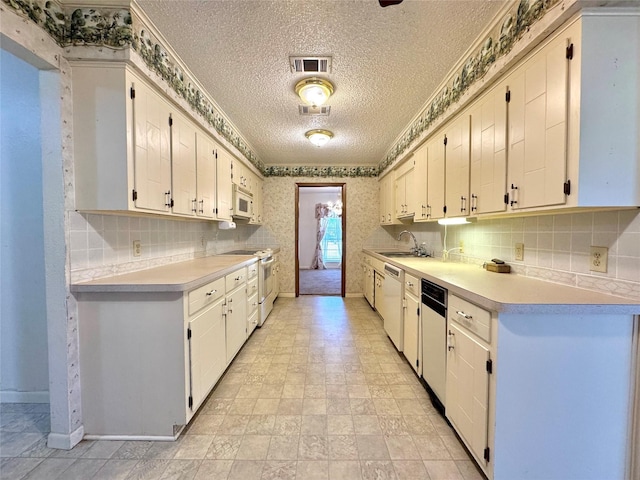 kitchen featuring white appliances, light countertops, visible vents, and wallpapered walls