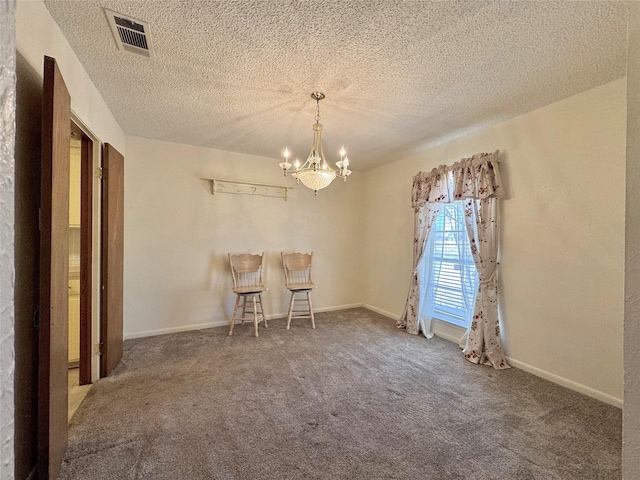 unfurnished dining area with visible vents, an inviting chandelier, carpet flooring, a textured ceiling, and baseboards