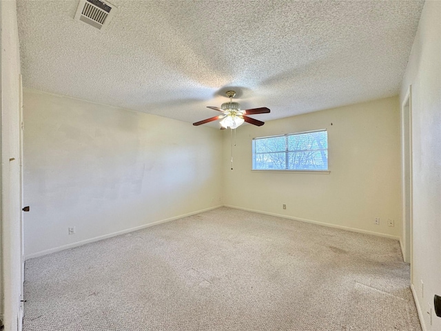 carpeted empty room featuring visible vents, ceiling fan, a textured ceiling, and baseboards