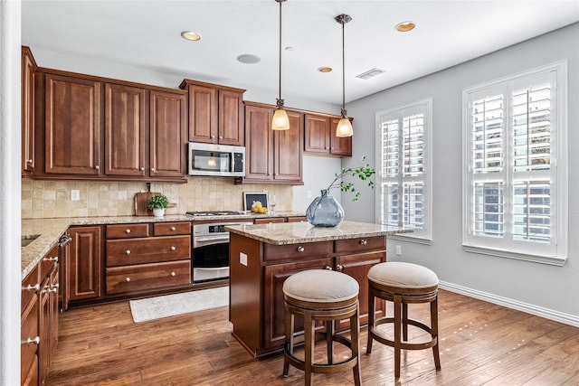 kitchen featuring tasteful backsplash, visible vents, a kitchen island, wood finished floors, and stainless steel appliances