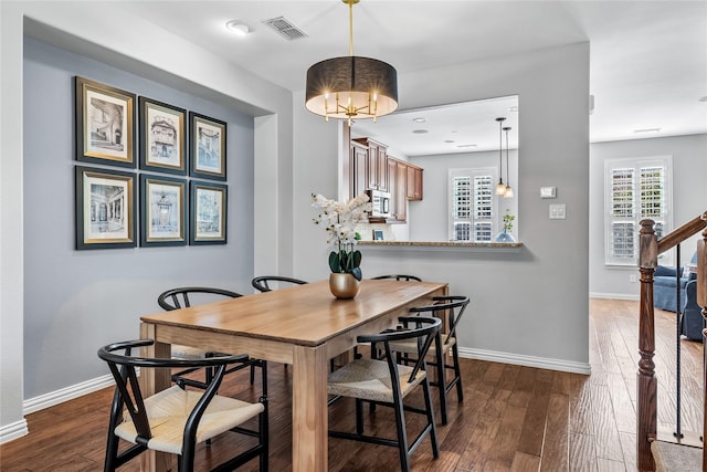 dining space featuring dark wood-style flooring, visible vents, baseboards, and stairs