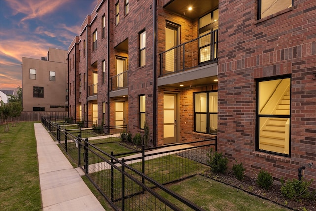 exterior space with fence, a lawn, and brick siding