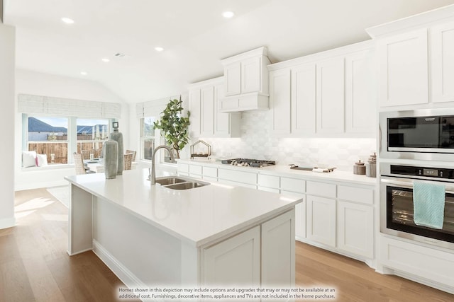 kitchen featuring light countertops, decorative backsplash, appliances with stainless steel finishes, vaulted ceiling, and a sink