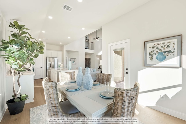 dining room with light wood-style floors, a high ceiling, visible vents, and recessed lighting