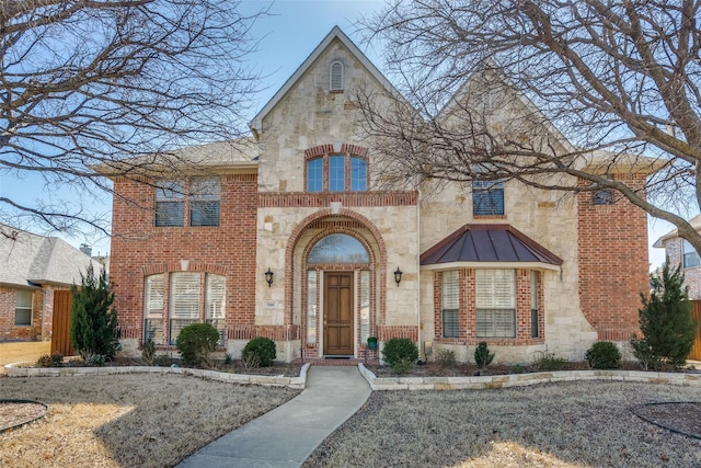 view of front facade featuring metal roof, stone siding, brick siding, and a standing seam roof