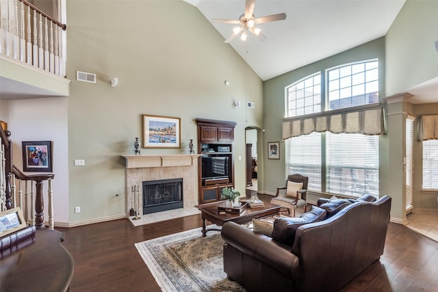 living area with a wealth of natural light, a tiled fireplace, wood finished floors, and visible vents