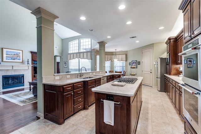 kitchen featuring a spacious island, visible vents, appliances with stainless steel finishes, a sink, and ornate columns