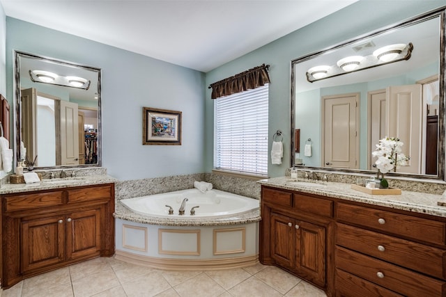 bathroom featuring tile patterned flooring, two vanities, a sink, and a bath