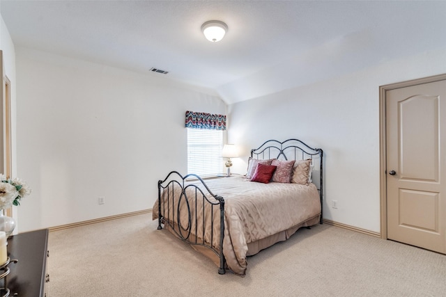 bedroom with lofted ceiling, light colored carpet, visible vents, and baseboards