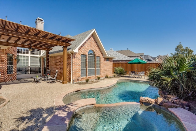 view of pool featuring a ceiling fan, fence, a patio area, a pool with connected hot tub, and a pergola