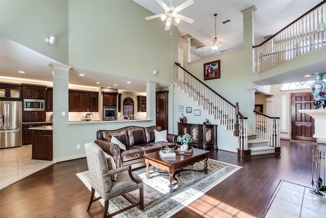 living room with a ceiling fan, stairway, decorative columns, and hardwood / wood-style flooring