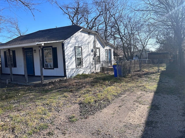 view of side of home with covered porch and fence