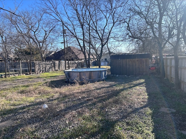 view of yard with a storage shed, an outdoor structure, a fenced backyard, and a fenced in pool