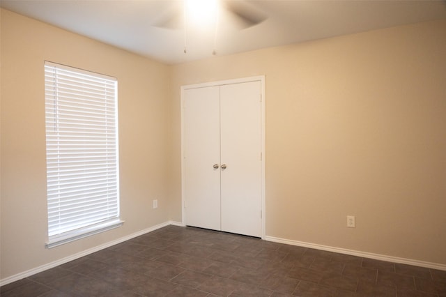 unfurnished bedroom featuring a ceiling fan, baseboards, and a closet