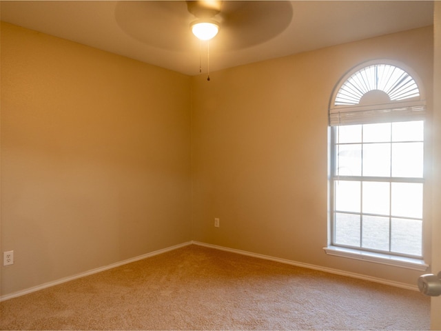 spare room featuring light carpet, plenty of natural light, baseboards, and ceiling fan