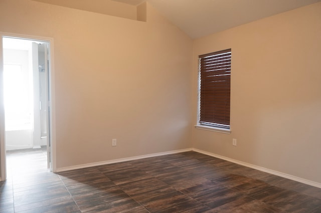 unfurnished room with dark wood-type flooring, lofted ceiling, and baseboards