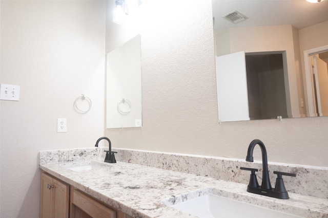 full bath featuring visible vents, a sink, and double vanity