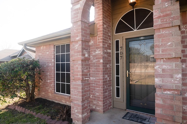 view of exterior entry featuring brick siding