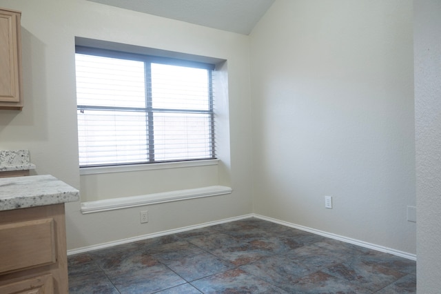 unfurnished dining area featuring lofted ceiling and baseboards