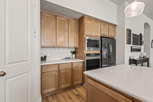 kitchen featuring light wood finished floors, tasteful backsplash, oven, built in microwave, and black refrigerator with ice dispenser