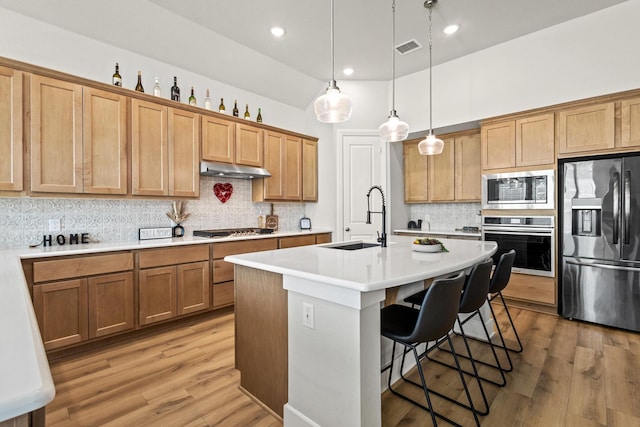 kitchen featuring visible vents, a breakfast bar area, appliances with stainless steel finishes, light countertops, and a sink