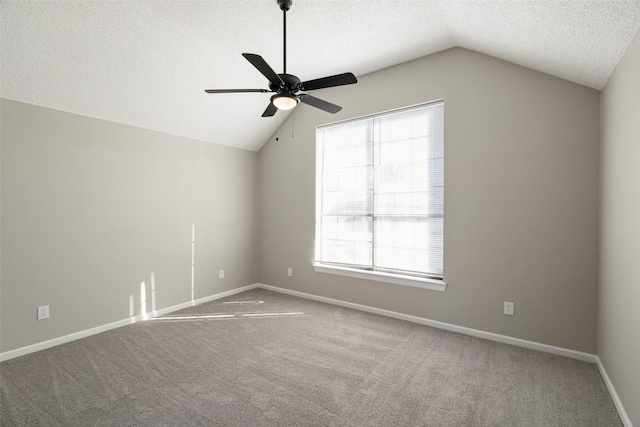 carpeted empty room with a wealth of natural light, lofted ceiling, a textured ceiling, and baseboards