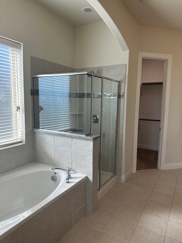 bathroom with a stall shower, a walk in closet, plenty of natural light, and a bath